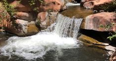 there is a small waterfall in the middle of some rocks and water flowing down it