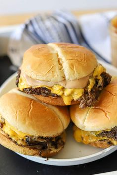 three cheeseburger sandwiches on a white plate