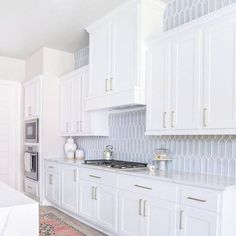 a kitchen with white cabinets and marble counter tops