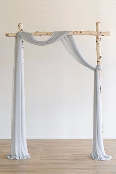 an arch made out of branches with white draping on the top and bottom