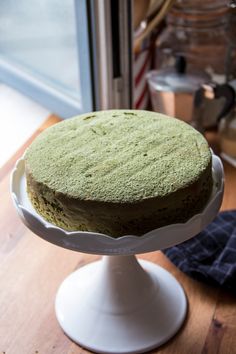 a green cake sitting on top of a white plate