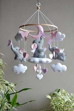 a baby mobile with elephants and hearts hanging from it's centerpiece in front of a potted plant