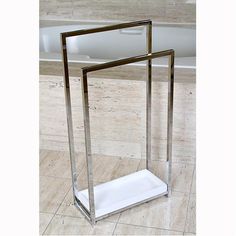 a glass and metal stand on the floor in front of a bathtub with tile floors