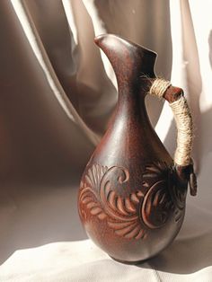 a brown vase sitting on top of a white sheet