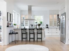 a large kitchen with white walls and wooden flooring, along with an area rug on the floor