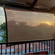 the sun is setting over mountains and trees from an outdoor area with metal railings