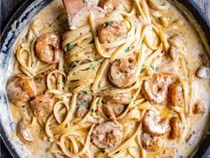 pasta with shrimp and sauce in a skillet on top of a wooden table, ready to be eaten