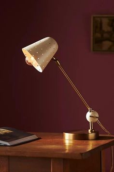 a desk lamp sitting on top of a wooden table in front of a purple wall