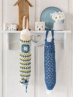 two crocheted umbrellas hanging from hooks on a white wall next to a birdhouse