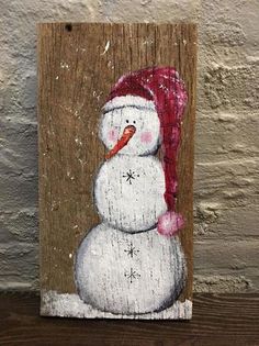 a wooden sign with a snowman wearing a red hat on it's head