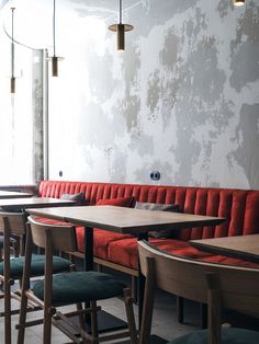 an empty restaurant with red booths and blue chairs, along with wooden tables in the middle