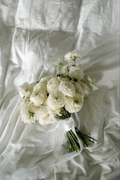 a bouquet of white flowers sitting on top of a white bed sheet covered in sheets