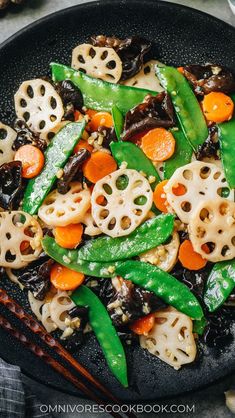 a black plate topped with stir fry vegetables