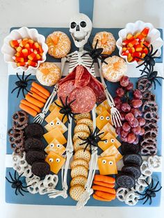 a tray filled with halloween treats on top of a blue tablecloth covered in skulls and bones