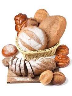 breads and pastries in a basket on a cutting board next to some nuts