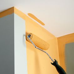 a person using a paint roller to paint a wall with yellow and gray colors on it