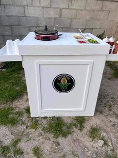 an outdoor table with food and drinks on the top in front of a brick wall