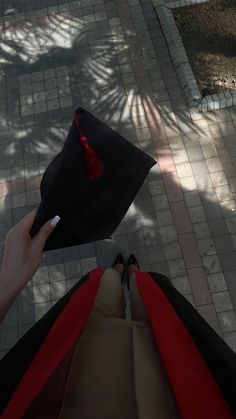 a person holding a graduation cap and pointing it at the ground with their foot in the air