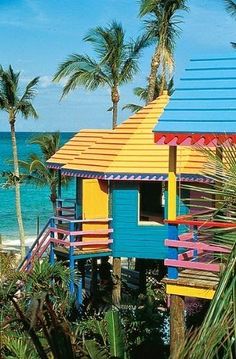 a colorful house on the beach with palm trees