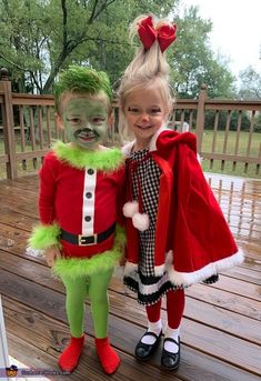 two children in costumes standing on a deck