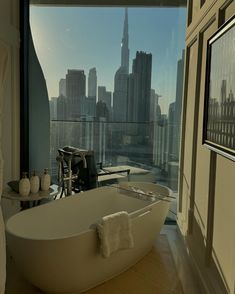 a bath tub sitting next to a window in a bathroom with a view of the city