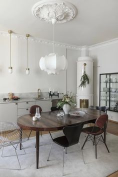 a dining room table with chairs around it and lights hanging from the ceiling above them