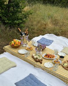 a picnic table with food and drinks on it in the middle of an open field