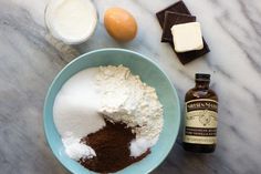 ingredients to make chocolate cake sitting on a marble counter top next to an egg and milk