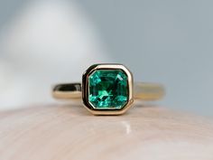 an emerald colored ring sitting on top of a piece of wood