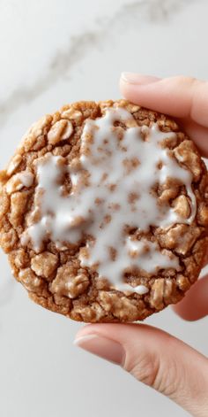 a hand holding a cookie with white icing