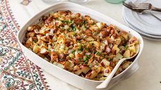 a casserole dish with potatoes and meat in it on a table next to silverware