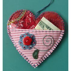 a red and white heart shaped ornament hanging on a green wall with money in it