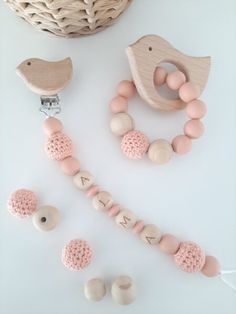 a wooden pacifier, rattler and beads on a white surface next to a wicker basket