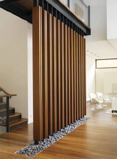 a wooden slatted wall in the middle of a wood flooring area next to a stair case