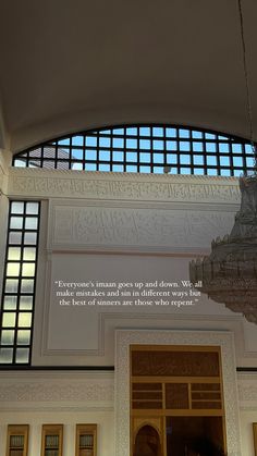 a chandelier hanging from the ceiling in front of a window with a quote on it