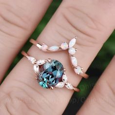 a woman's hand holding two rings with an oval shaped blue and white stone