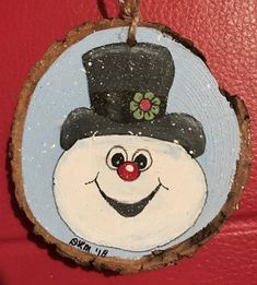 a painted snowman ornament hanging on a red door with a black top hat