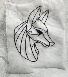 a drawing of a wolf head on a piece of paper with white fabric behind it