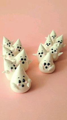 small white ceramic figurines with black dots on them sitting on a pink surface