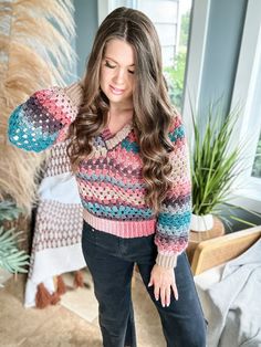 a woman is posing for the camera wearing a colorful sweater