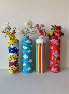 three colorful vases with flowers in them