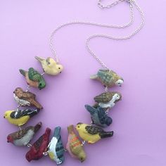 a necklace made out of small birds on a purple surface with a chain attached to it