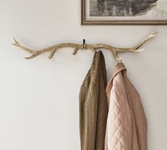 a coat rack with two coats hanging from it's sides next to a painting on the wall