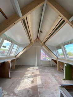 an unfinished room with multiple windows and wooden beams