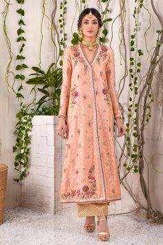 A captivating shade of peach over a canvas of jacquard silk net, this chogha features myriad of colorful resham work in beautiful floral embroidery, further enhanced with dabka, sequins, pearls, beads & crystals in rose gold, antique gold &silver tones on neckline, hem, sleeves & back. Beautifully Hand-crafted tassels for additional style element. A classy Raspberry & Gold Jacquard Chunri dupatta adds a beautiful pop of color and dhanak embellished tissue izaar elevates the festive look of this Resham Work, Designer Outfit, Shades Of Peach, Potli Bags, Festive Look, Pakistani Designers, Floral Embroidery, Antique Gold, Crystal Beads