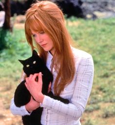 a woman holding a black cat in her arms