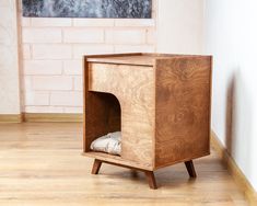 a small wooden cabinet sitting on top of a hard wood floor next to a brick wall