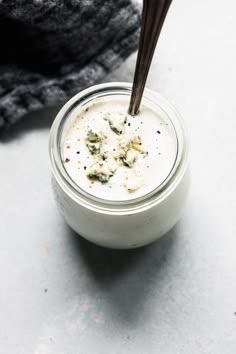 a glass jar filled with blue cheese dressing on top of a white counter next to a gray towel