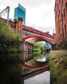 a red bridge over a river next to tall buildings