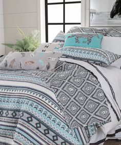 a bed with blue and white comforters on top of it in a room next to a window